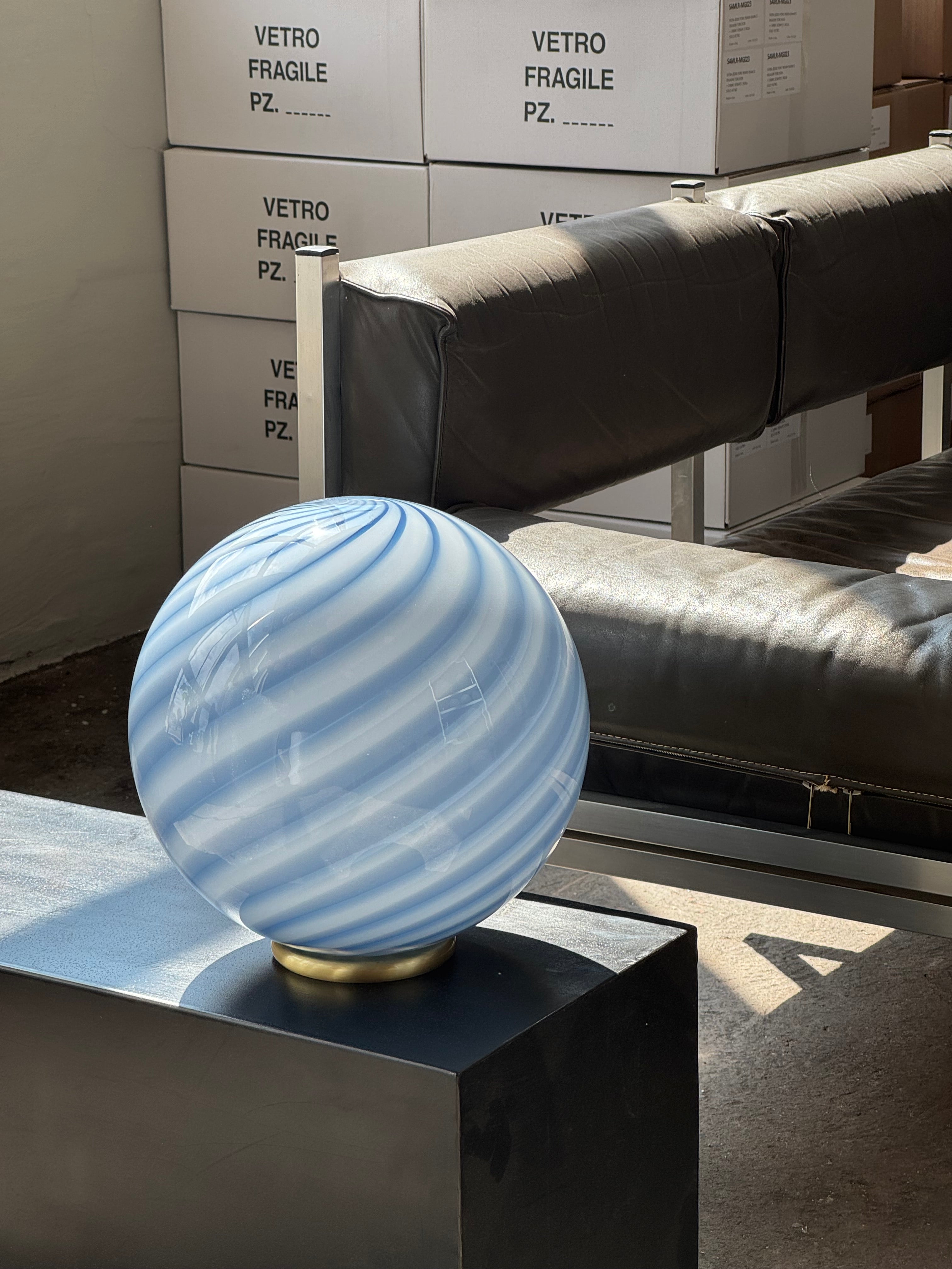 Ny Murano Candy bordlampe med blå swirl. Mundblæst glas i rund form. E27 fatning samt base med overflade i børstet messing.
Den perfekte størrelse til dit natbord, indbygget reol eller vindueskarm.