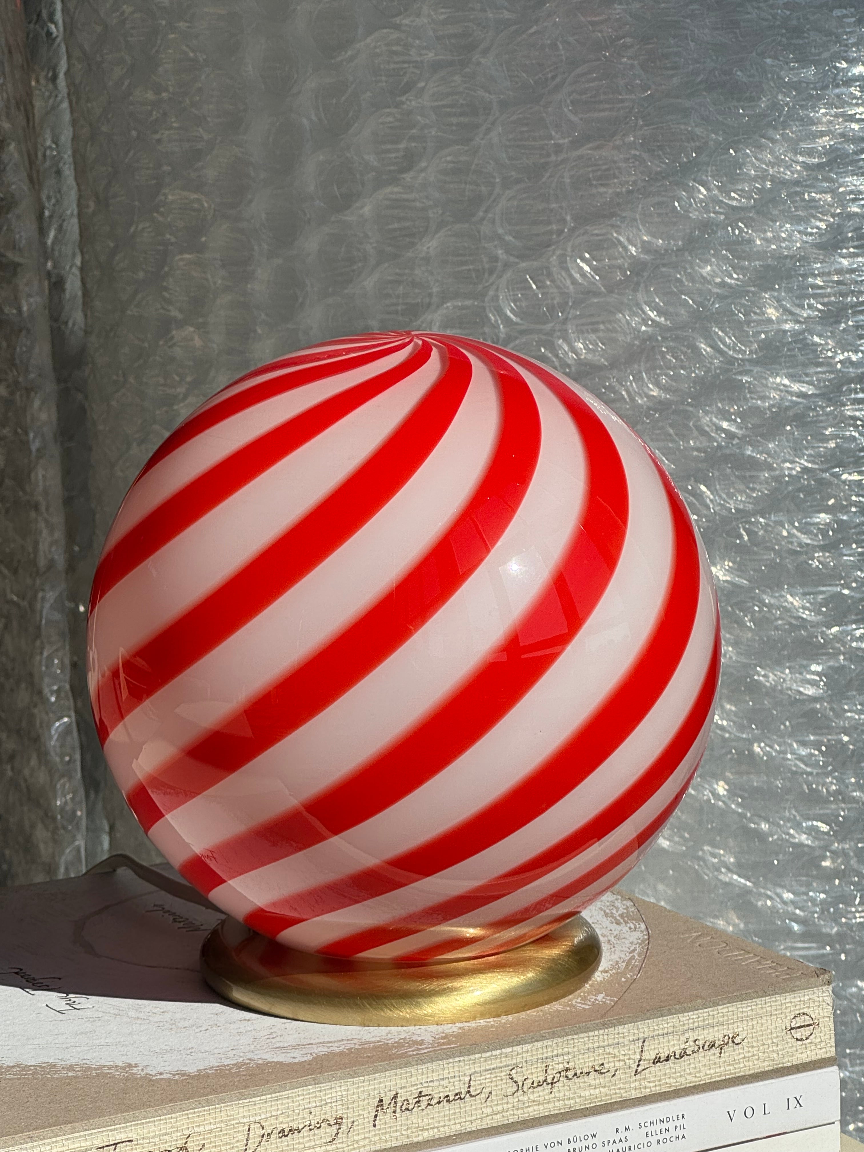 Ny Murano Candy bordlampe i en bolsje kombination af rød og hvid swirl. Mundblæst glas i rund form. E27 fatning samt base med overflade i børstet messing.
Den perfekte størrelse til dit natbord, indbygget reol eller vindueskarm.
Håndlavet i Italien.
D:20 cm
Vægt ca. 1 kg.
