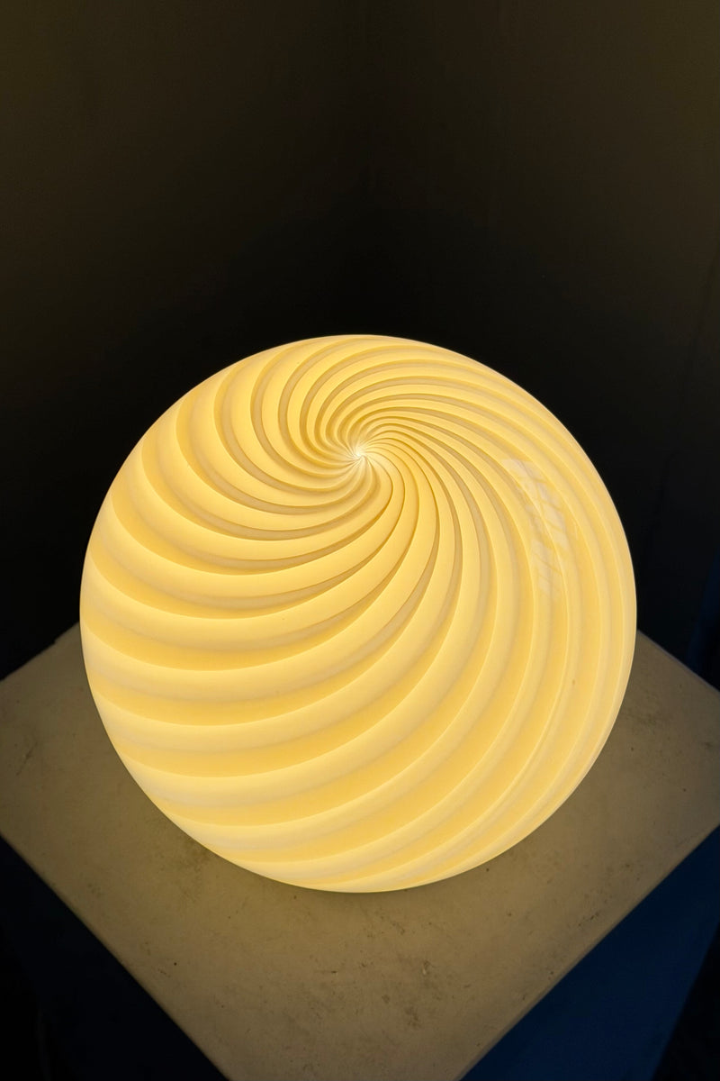 Murano bordlampe i gul swirl mønster, set ovenfra med en blød lysstyrke og elegant form