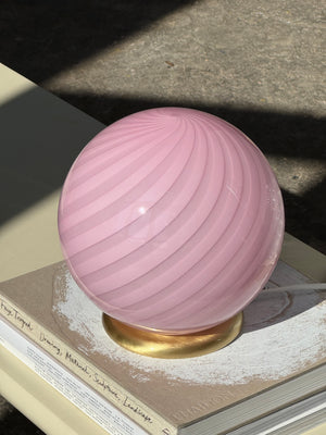 Murano table lamp in bubble gum color with swirl pattern, viewed from the side on a table with books