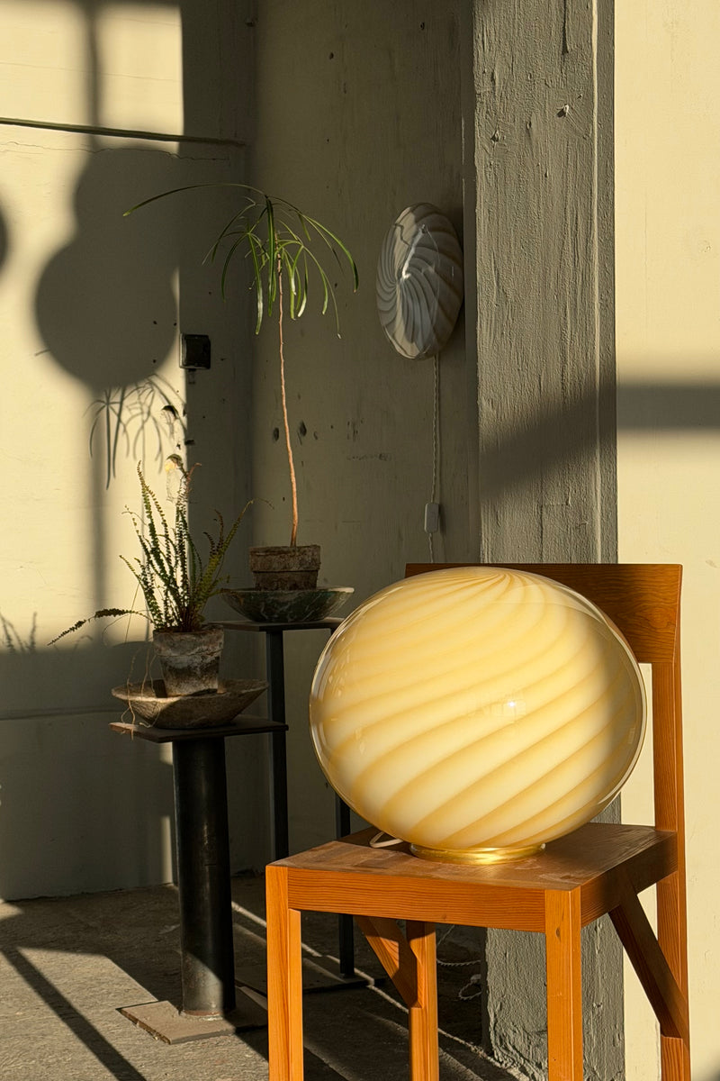 smuk Murano gulvlampe med gul swirl mønster, placeret på en træstol i et lyst rum