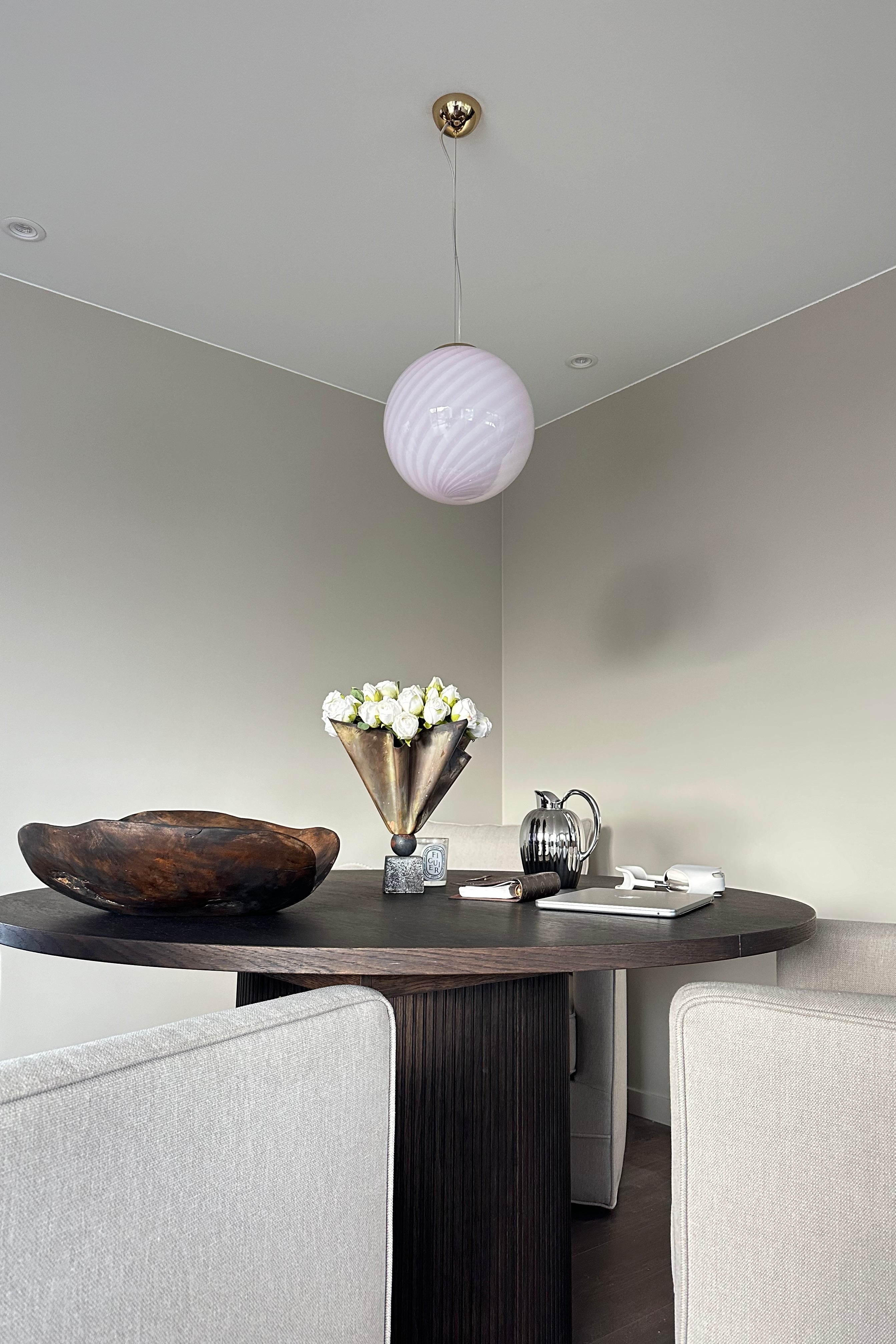 Murano pendel i myk lyserosa med swirl-mønster hengende over et rundt bord i en moderne stue