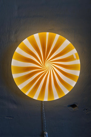 grand lustre plafonnier Murano à bandes jaunes/blanches en motif swirl, vu de côté contre un mur sombre