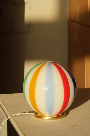 Murano Lampe de table Candy Beach Ball avec motif tourbillonnant coloré vue de côté, placée sur une table