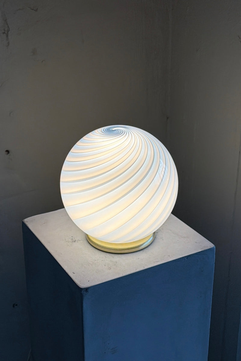 Murano candy bordlampe i blå swirl mønster, rund form med blød glød, placeret på en stenplade