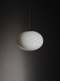 elegant white Murano pendant with swirl pattern, hanging in a modern room in a play of shadows