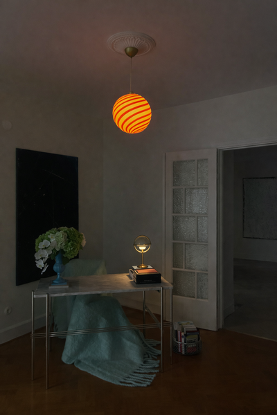 Murano pendel med orange/hvid swirl mønster hængende over skrivebord i en stilfuld stue