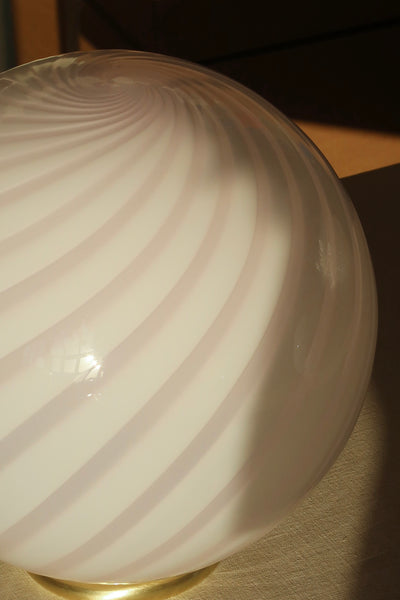 soft pink Murano table lamp with swirl pattern seen from the side, round shape with glossy surface