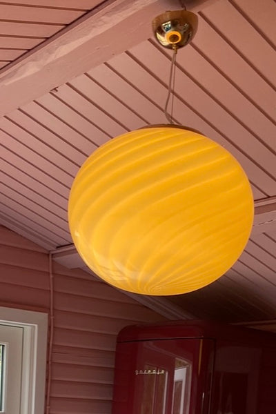 stor Murano pendel i gul med swirl mønster, set oppefra i en hyggelig indretning