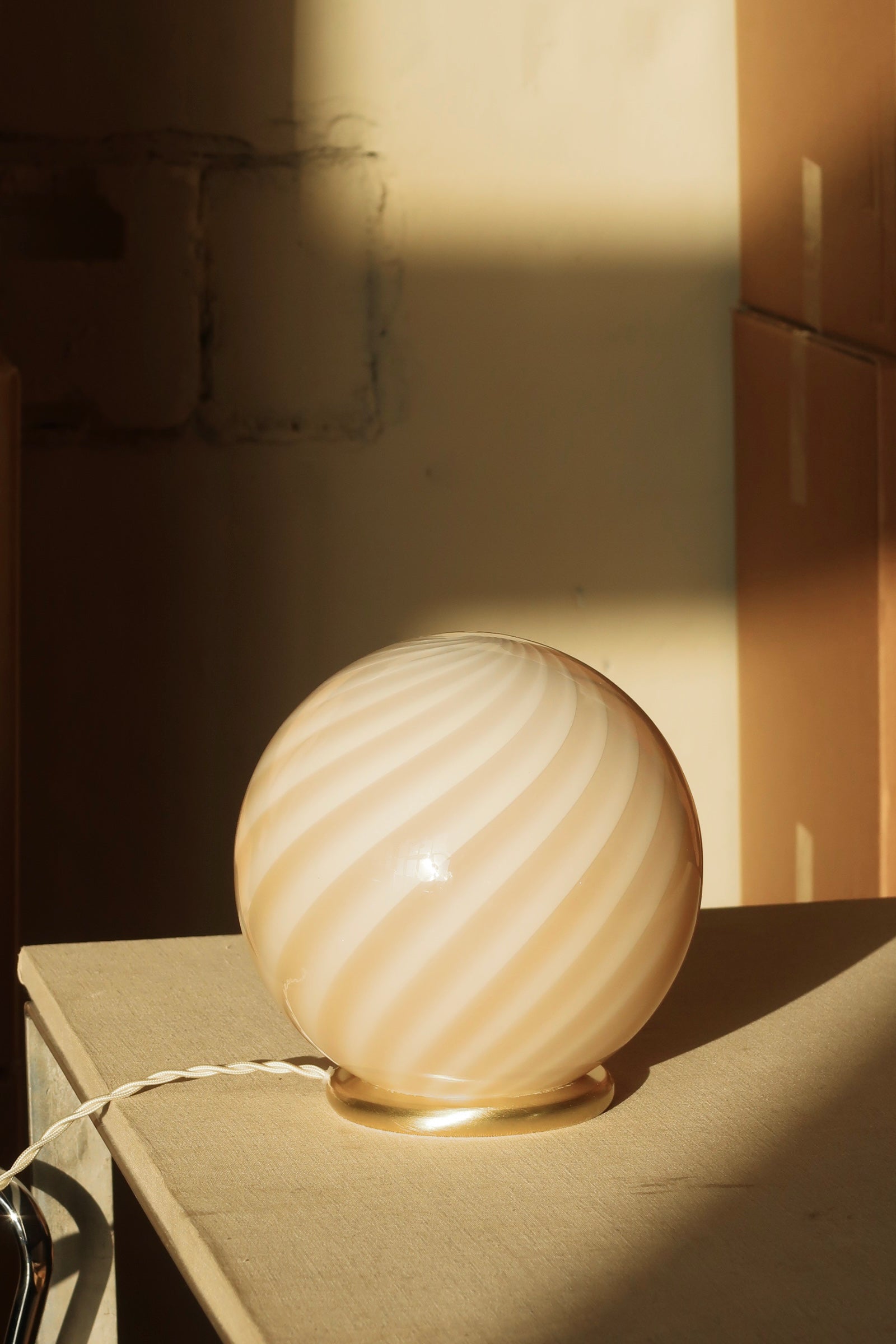 smuk Murano bordlampe med karamel/creme swirl mønster, set fra siden i et solbeskinnet rum