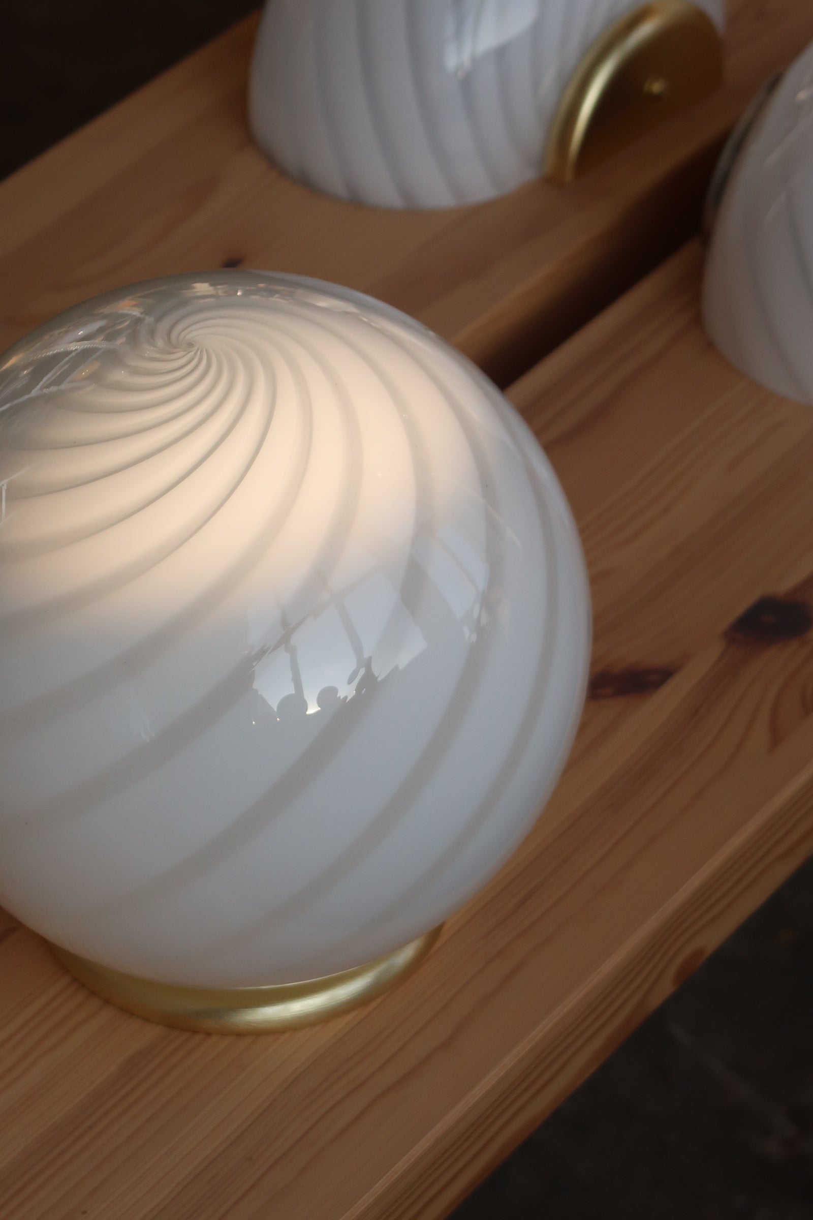 Murano table lamp with white swirl pattern in dense construction, seen from the side on a wood surface