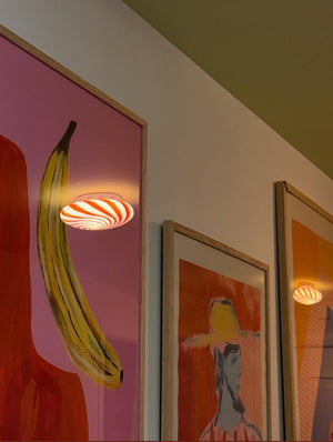 Murano Candy ceiling light with red/white swirl pattern, elegantly placed on the wall beside a colorful art panel