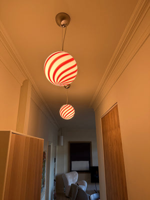 Murano suspension en bordeaux rouge/motif swirl blanc suspendue dans une pièce lumineuse au décor moderne